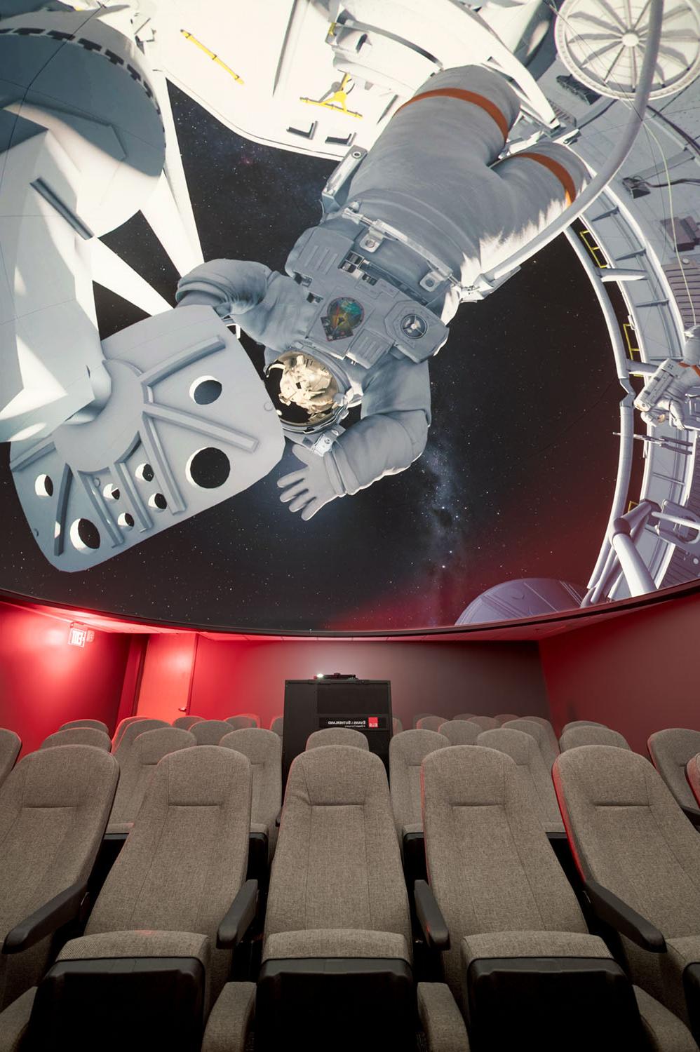 天文馆的座位和穹顶，屏幕上有太空行走的图像